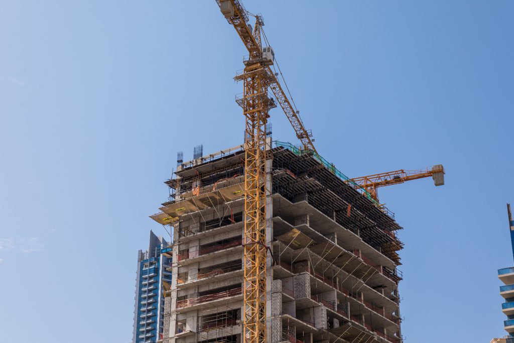 Obra de alto padrão em andamento, com estrutura de concreto e operários trabalhando na fundação do edifício em Balneário Camboriú.