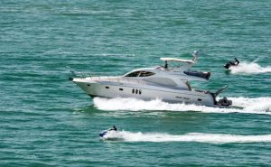Lancha de luxo navegando em Itajaí com jet skis ao redor — habilitação náutica e lazer no litoral catarinense