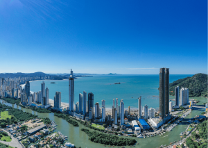 Panorâmica aérea de Balneário Camboriú com arranha-céus ao longo da orla curva e mar azul-turquesa ao fundo