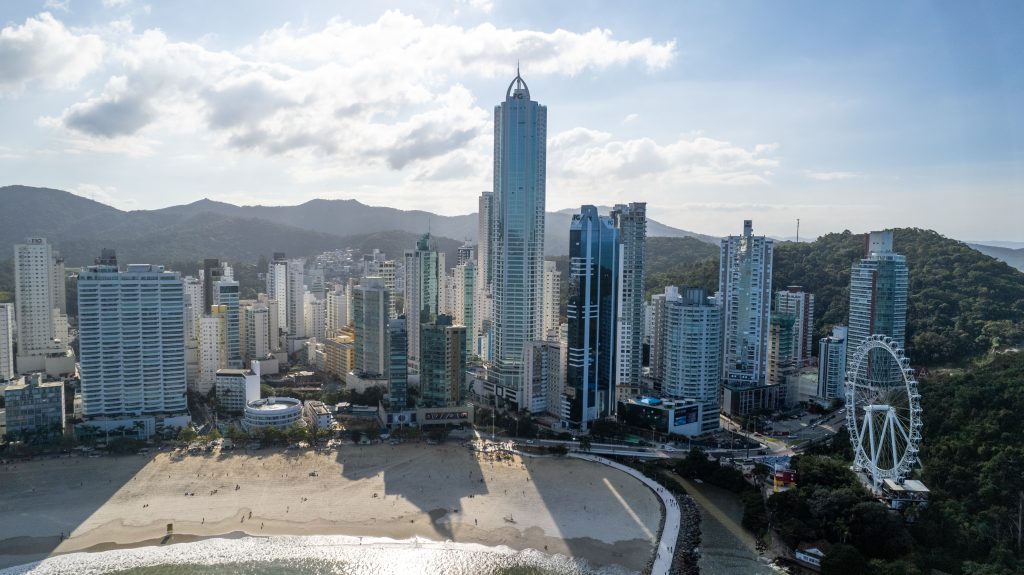 Torre Infinity Coast em Balneário Camboriú com fachada de vidro esverdeado, coroamento pontiagudo e vista para o mar