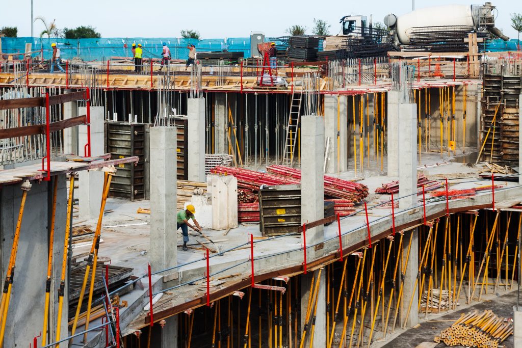 Obra de alto padrão em andamento, com estrutura de concreto e operários trabalhando na fundação do edifício em Balneário Camboriú.