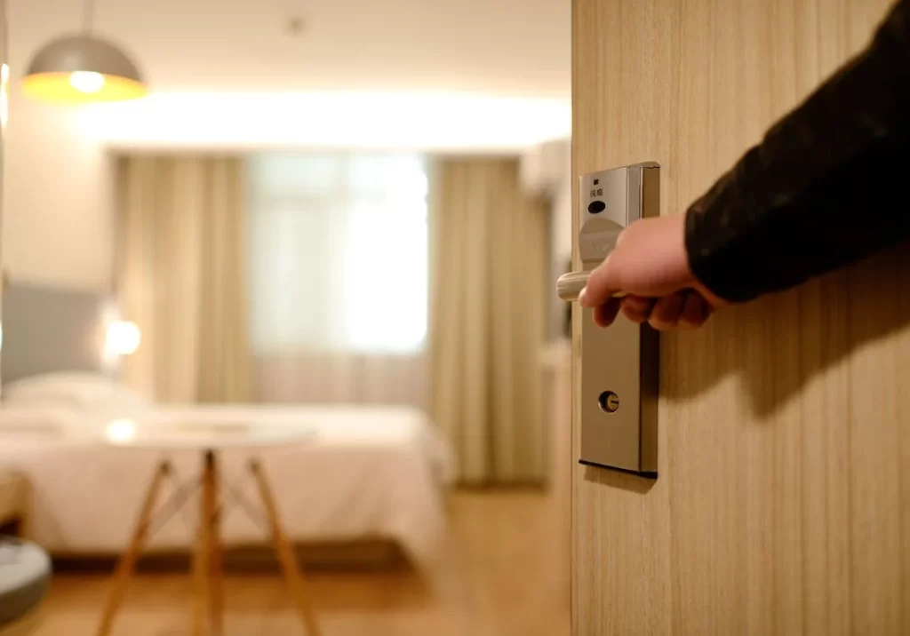 "Pessoa abrindo porta de quarto mobiliado em apartamento