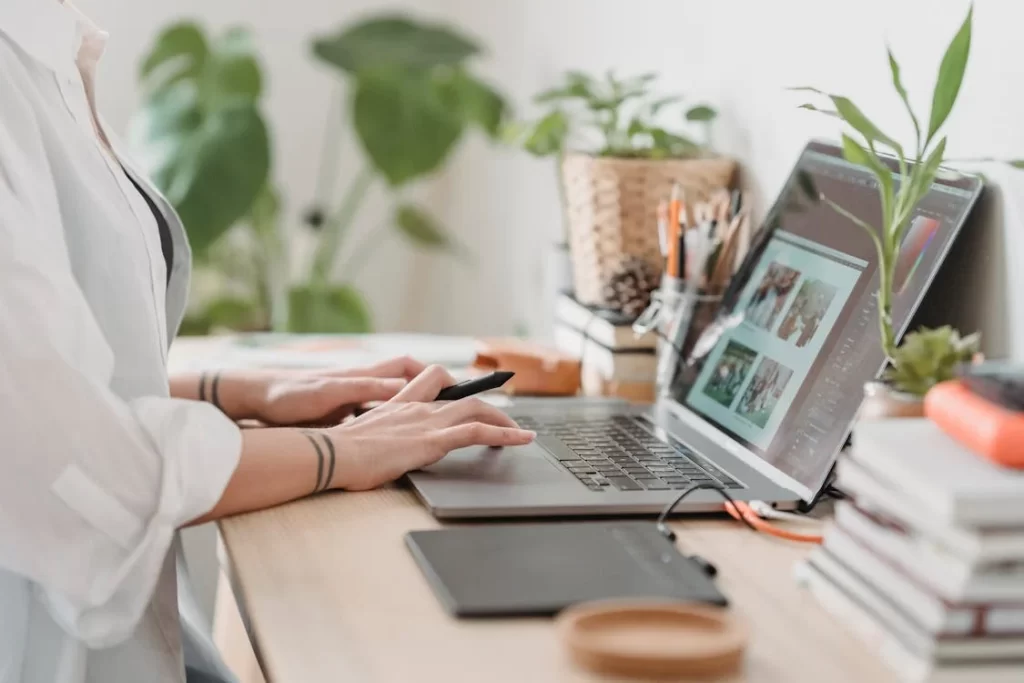 Mãos usando caneta digital e notebook em uma estação de trabalho criativa