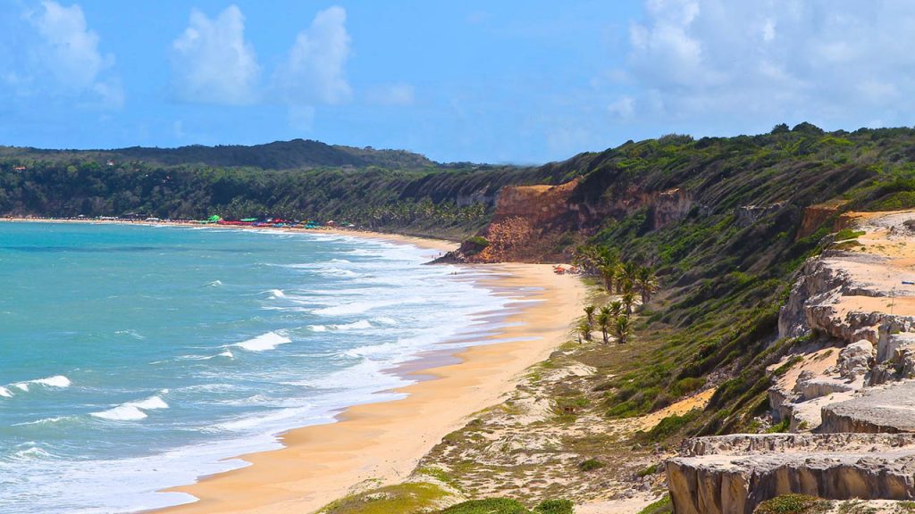 Falésias avermelhadas e ondas cristalinas na Praia de Pipa em Tibau do Sul (RN), margeada por vegetação costeira