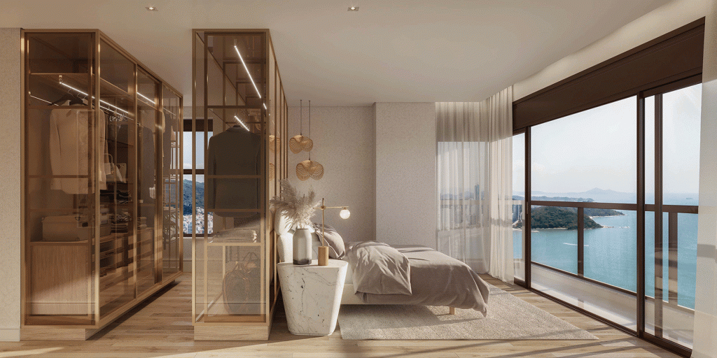 Suíte master contemporânea com closet envidraçado, piso de madeira, cama de casal com roupa de cama neutra e ampla janela de vidro com vista para o mar.